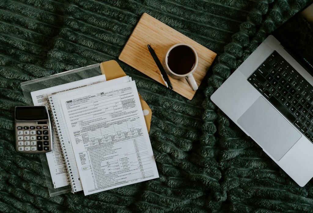 Laptop, dokumenti i kalkulator za planiranje cijene freelance projekta