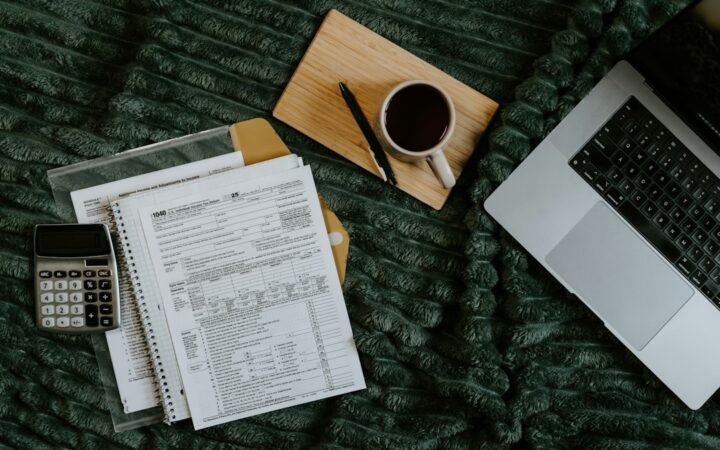 Laptop, dokumenti i kalkulator za planiranje cijene freelance projekta